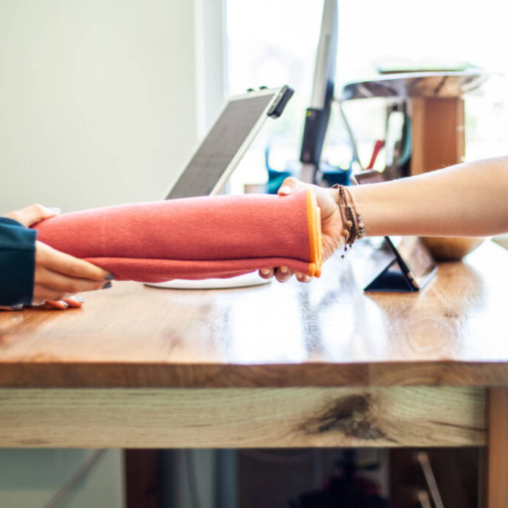 Hands exchanging a red towel at a counter at Sol Hot Yoga Studio