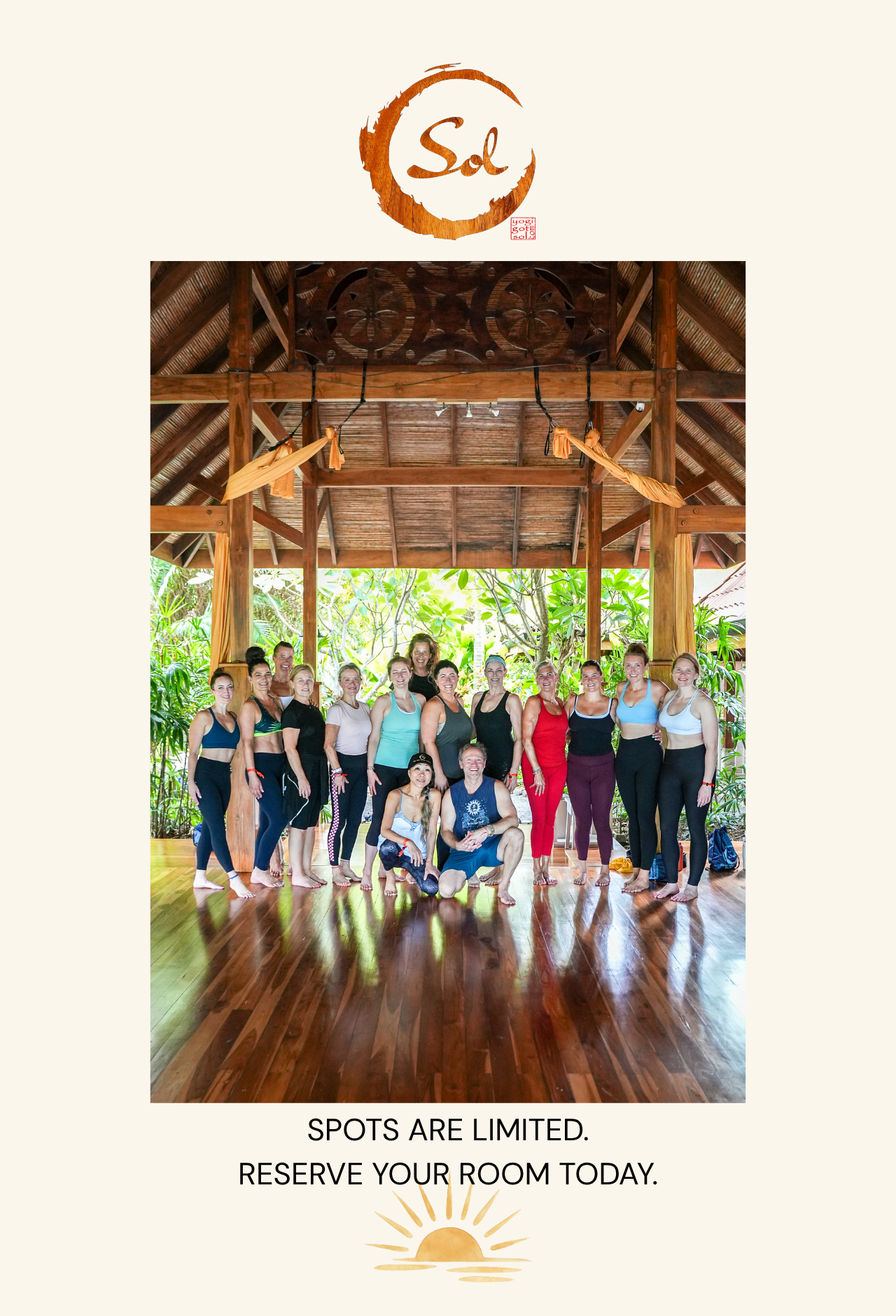 Group of about 20 people in workout attire posing together inside a wooden pavilion with tropical greenery outside behind them.