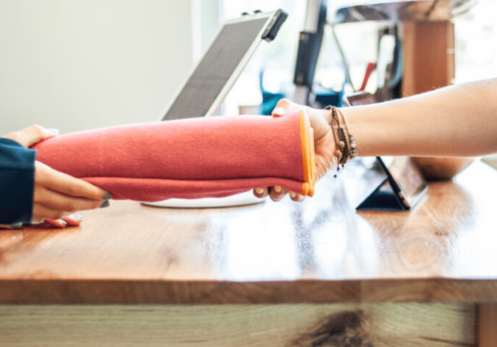 Hands exchanging a red towel at a counter at Sol Hot Yoga Studio